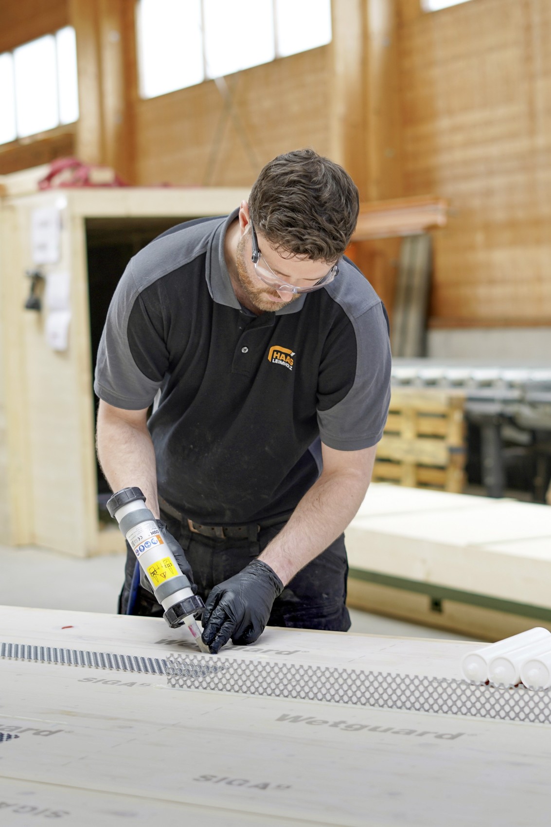 Ein Mitarbeiter der Leimholz Haag AG verleimt die Schubverbinder mit den Holzdecken-Elementen.