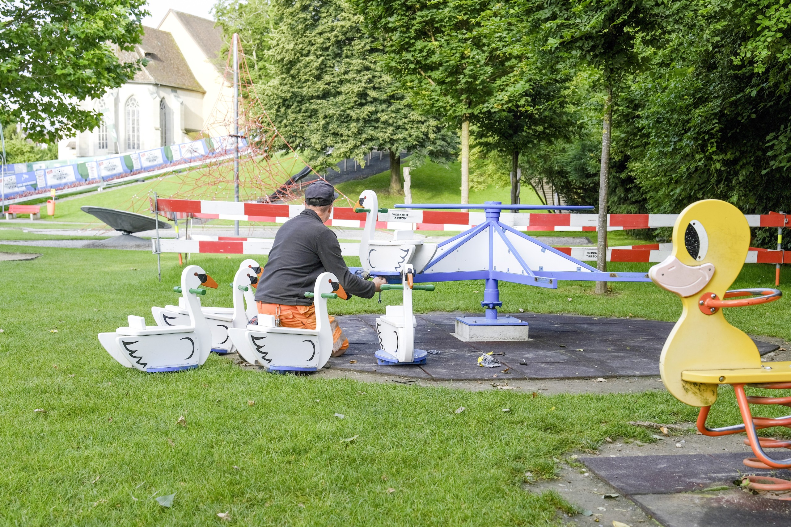 Nach dem Seenachtsfest schraubt ein Werkhof-Mitarbeitender die Holz-Schwäne auf dem Schlossspielplatz wieder an das Drehkarussell. Als Schutzmassnahme vor Vandale-Akten wurden diese für die Dauer der Veranstaltung entfernt.